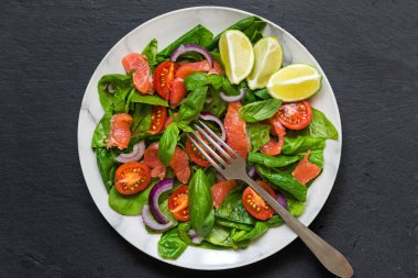 Ispanak, cherry domates, kırmızı soğan ve fesleğen çatal beyaz mermer plaka ile somon salatası. sağlıklı gıda kavramı. üstten görünüm