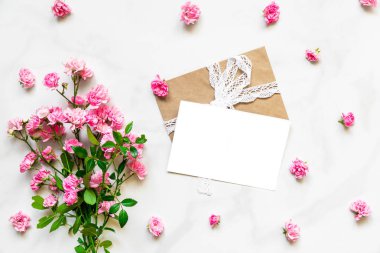 boş beyaz tebrik kartı ile çerçeve içinde pembe gül çiçek çiçek tomurcukları beyaz mermer zemin üzerine yapılmış. kadar alay et. düz yatıyordu. tatil kavramı. üstten görünüm