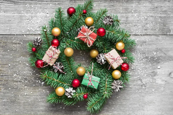 Noel çelenk süsleri ve hediye kutuları rustik ahşap masa üzerinde karla kaplı. üstten görünüm. düz lay