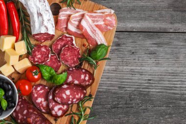 Salam, pastırma, sosis, peynir, zeytin, domates ve otlar dilimlenmiş. Ahşap masa üzerinde et meze tabağı. kopya alanı ile üstten görünüm