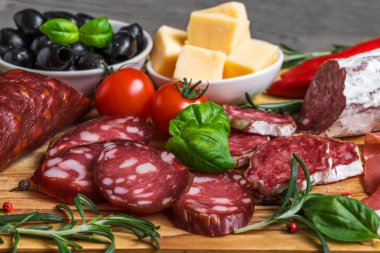 Lezzetli salam, sosis, peynir, tütsülenmiş sosis, zeytin, domates ve otlar ile yemek tepsisi. Ahşap masa et tepside. yakın çekim