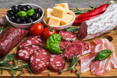 Salam, pastırma, sosis, peynir, zeytin, domates ve otlar dilimlenmiş. Ahşap masa üzerinde et meze tabağı. yakın çekim