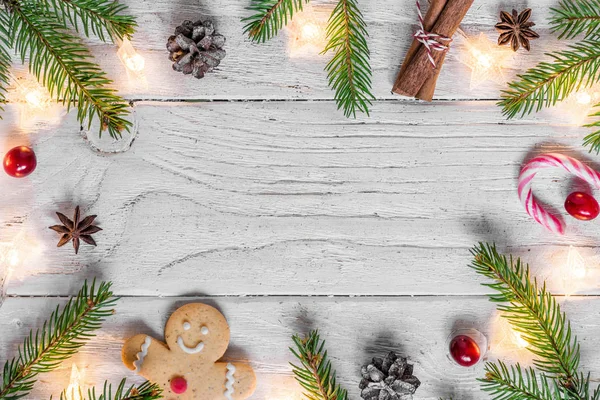 Christmas composition with christmas lights, food, fir tree, berries and pine cones on white wooden background with copy space for your text. top view. flat lay