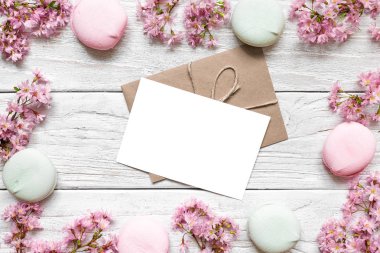 mockup tebrik kartı çerçeve içinde pembe çiçek açması bahar dalları kiraz veya armut ve macaroons kopya alanı ile yapılmış. üstten görünüm. düz lay
