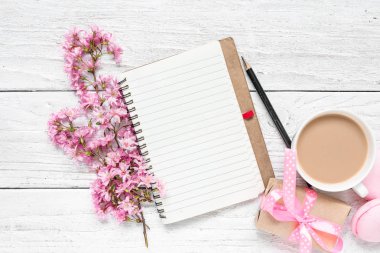 boş kağıt Not defteri, macarons, Beyaz ahşap masa kahve Kupası ve hediye kutusunda pembe çiçek açması çiçeklerle bahar. düz yatıyordu. metin için yer ile üstten görünüm