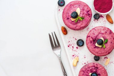 ham yaban mersini ve acai vegan cheesecakes taze çilek, nane, fındık ve çatal ile. sağlıklı vegan gıda kavramı. üstten görünüm. düz lay