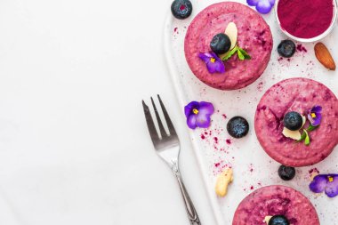 yaban mersini ve acai vegan kaju kek ile taze çilek, yenilebilir çiçekler, nane, deli. sağlıklı vegan gıda kavramı. üstten görünüm. düz lay