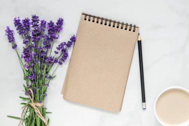 Yaratıcı düzen lavanta çiçekleri, boş not defteri ve beyaz mermer zemin üzerine kahve fincanı ile yaptı. Düz yatıyordu. Üstten Görünüm. Düğün arka plan. Bahar kavramı