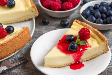 Cheesecake taze ahududu, yaban mersini, reçel ve beton zemin üzerine nane ile pasta dilimi ile. yakın çekim. lezzetli kahvaltı
