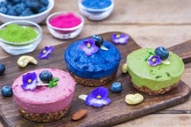 matcha, acai, kelebek bezelye çay, taze meyveler, nane ve fındık ile çeşitli çiğ vegan kek. sağlıklı vegan gıda kavramı. yakın çekim