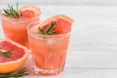Biberiye ve beyaz arka plan üzerinde buz ile bardaklarda greyfurt kokteyller. Sağlıklı narenciye yaz içeceği. yakın çekim