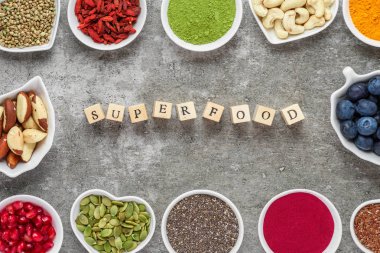 superfoods gri bir arka plan üzerinde ürün yelpazesine. Matcha, acai, zerdeçal, meyve, meyveler, fındık ve tohumlar. Sağlıklı vegan gıda. Üstten Görünüm