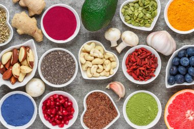 gri bir arka plan üzerinde sağlıklı vegan gıda ürün yelpazesine. Matcha, acai, zerdeçal, meyve, çilek, avokado, mantar, fındık ve tohum. Superfood Üstten Görünüm