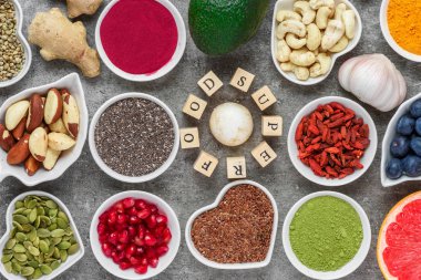 Superfood as acai, turmeric, matcha, seeds, blueberry, goji, ginger, grapefruit, mushrooms, pomegranate and nuts on dark concrete background vegan food concept top view clipart