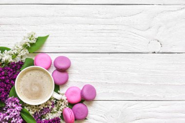 metin için kopya alanı ile beyaz ahşap masa üzerinde makarna ve kapuçino fincan ile bahar leylak çiçek buketi