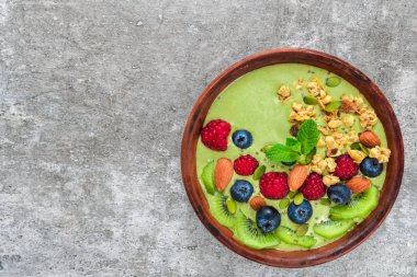 taze çilek, meyve, granola, fındık ve sağlıklı vegan kahvaltı için tohum ile yeşil matcha çay smoothie kase