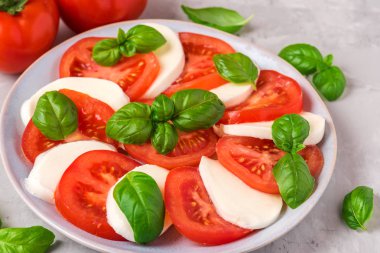 olgun domates ve mozzarella peyniri ile caprese salatası, beton arka plan üzerinde taze fesleğen yaprakları. İtalyan yemekleri