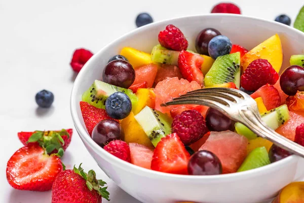 Obstsalat mit Wassermelone, Erdbeere, Kirsche, Blaubeere, Kiwi, Himbeere und Pfirsichen in einer Schüssel mit Gabel — Stockfoto