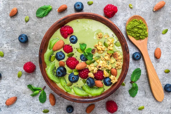 Ciotola di frullato di tè verde matcha con frutta fresca, bacche, noci, semi e muesli con un cucchiaio per una colazione sana — Foto Stock
