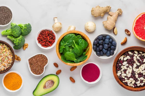 Superalimentos sobre mesa de mármol blanco. verduras, acai, cúrcuma, frutas, bayas, frutos secos y semillas. Alimento saludable — Foto de Stock