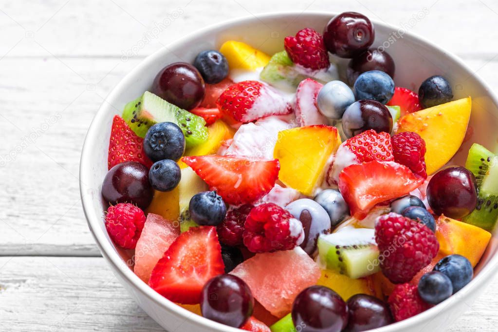fruit salad with yogurt, watermelon, strawberry, cherry, blueberry, kiwi, raspberry and peaches in a bowl. healthy food