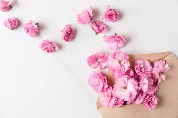 Розовые цветы вишни в конверте с бутонами на белом мраморном столе. Квартира лежала, вид сверху. свадебный фон — стоковое фото