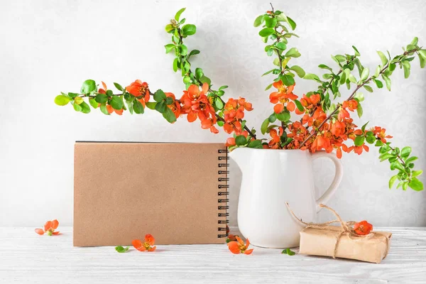 Ακόμα ζωή με μια όμορφη άνοιξη πορτοκαλί λουλούδια, φλιτζάνι τσάι και κενό σημειωματάριο χαρτί σε λευκό τραπέζι. μακέτα — Φωτογραφία Αρχείου