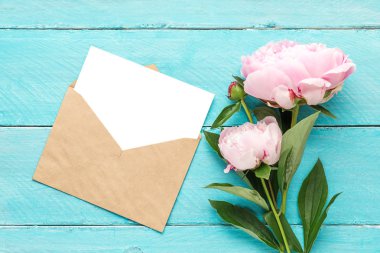 düğün davetiyesi. mavi ahşap arka plan üzerinde şakayık çiçek buketi ile boş tebrik kartı ve zarf. düz yatıyordu