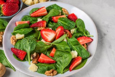 çilek salatası, ıspanak yaprakları, parmesan peyniri ve beton arka plan üzerinde ceviz. sağlıklı diyet gıda
