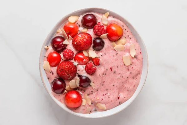 smoothie bowl or nice cream made of frozen bananas and berries with fresh berries, nuts and seeds