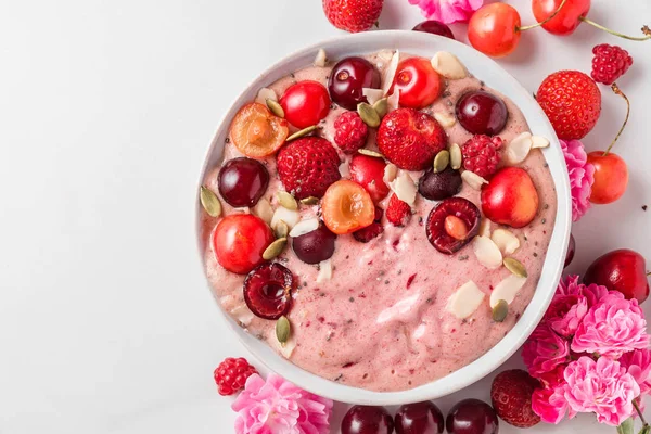 healthy diet breakfast. smoothie bowl or nice cream made of frozen bananas and berries with fresh berries, rose flowers