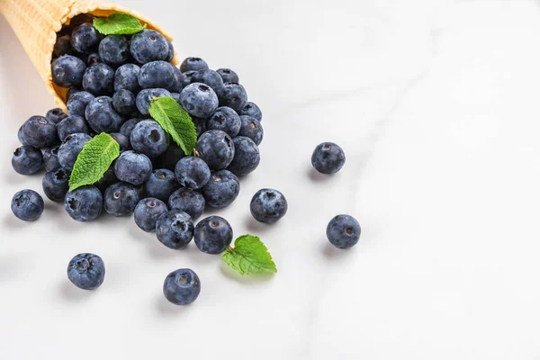 Blueberries with mint in waffle ice cream cone on white marble background. summer food concept — Stock Photo, Image