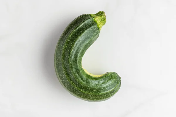 Trendy ugly organic zucchini vegetable from home garden on white marble table. top view — Stock Photo, Image