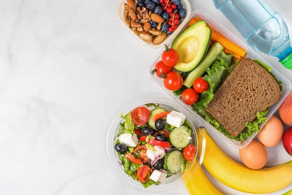 健康午餐盒,包括三明治、希腊沙拉、蔬菜、坚果、浆果、香蕉、鸡蛋、鳄梨、桃子和水 — 图库照片