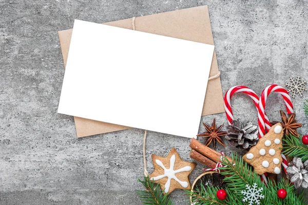 Köknar dalları, süslemeler, böğürtlenler, şekerler ve çam kozalakları içeren Noel tebrik kartı beton arka planda çakışıyor.