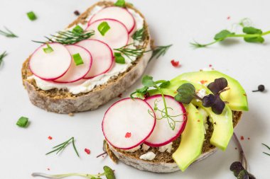 Sağlıklı bir bahar avokadosu, süzme peynirli turp tostu, lahanalar ve beyaz mermer masa üzerine biber sağlıklı bir diyet kahvaltısı için. Kapat.