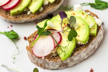 Beyaz mermer masada kahvaltıda turplu, peynirli, lahanalı ve biberli avokado tostları. Sağlıklı beslenme atıştırmalıkları. Kapat.