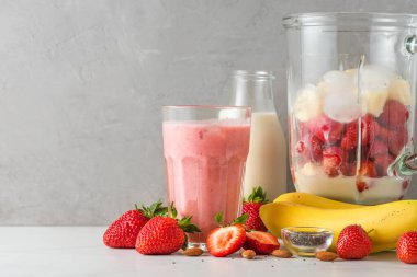 Bardak çilek ve muzlu smoothie ya da sağlıklı içecek yapmak için blender 'da taze sulu malzemelerle sulu milkshake. Yemek pişirme konsepti