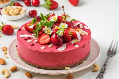 Çiğ çilek ve kaju peynirli kek ya da çatallı taze çilek, kiraz ve çiçekli kek. Kapat. Sağlıklı vejetaryen yemeği.