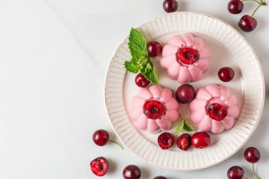 Taze böğürtlenli, naneli ve kaşıklı vişneli panna cotta tatlısı. Sağlıklı İtalyan yemeği tatlısı. Kopyalama alanı olan üst görünüm