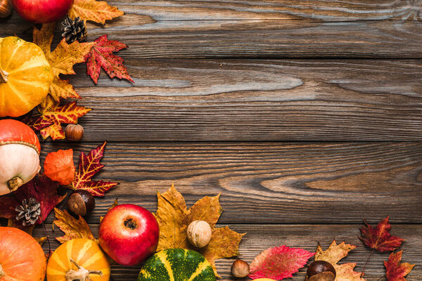 Thanksgiving, Halloween or autumn background. Fall composition with pumpkins, apples, leaves, dry flowers and nuts on rustic wooden table. Flat lay, top view, copy space