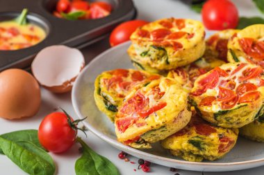 Keto ya da düşük karbonhidratlı diyet kahvaltı. Yumurta fincanları ya da ıspanaklı omlet ve bir tabak dolusu domates ve kek fincanı. Yemek konsepti. Kapat.
