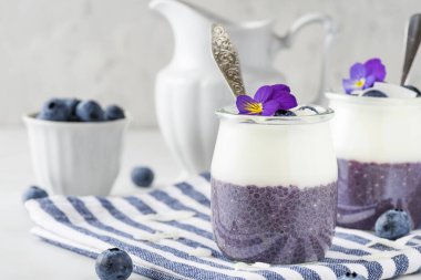 Taze böğürtlenli, hindistancevizli yoğurtlu, chia pudingli ve yenilebilir çiçeklerden oluşan sağlıklı bir kahvaltı.