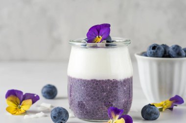 Taze meyve, hindistancevizi yoğurdu, chia pudingi ve yenilebilir çiçeklerden oluşan sağlıklı bir kahvaltı.