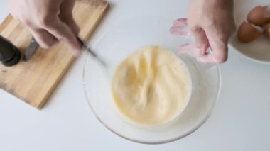 Adam kahvaltı hazırlıkları sırasında cam kasede yumurta çırpıyor ve süt karıştırıyor. Omlet ya da çırpılmış yumurta. Sağlıklı yiyecekler. Üst görünüm.