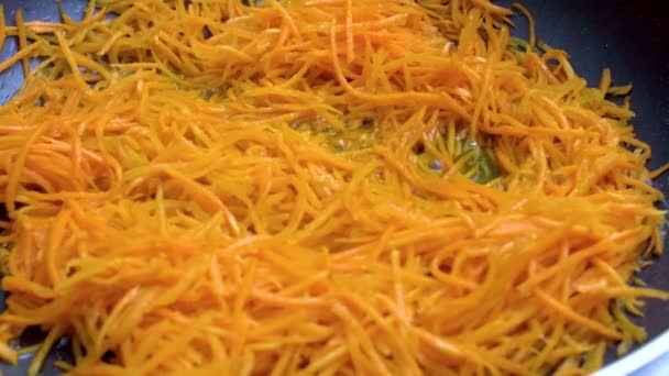 Тертая морковь жарится в сковороде на масле . — стоковое видео