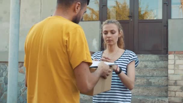 De postbode levert een perceel voor een jonge vrouw — Stockvideo