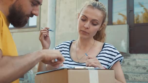 De postbode levert een perceel voor een jonge vrouw — Stockvideo