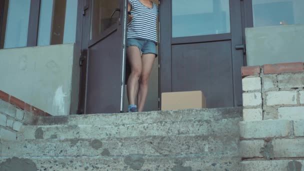 Paket auf matte Außentür, die sich öffnet und Frau abholt — Stockvideo