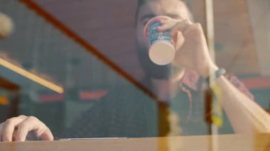 Bir smartphone ve içecek kahve ile kafede oturan bir adam çekim